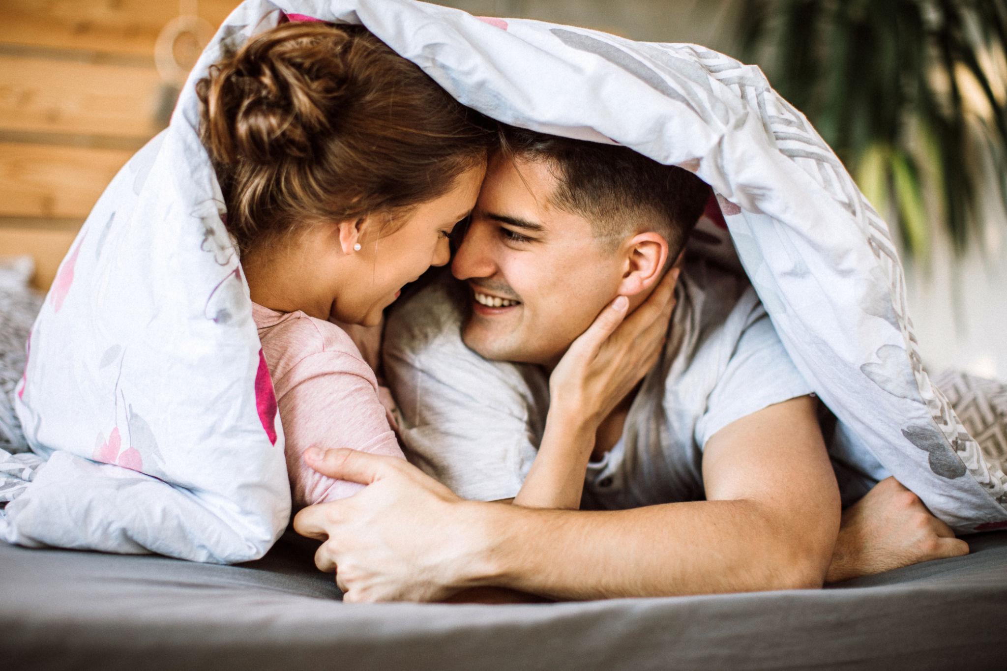 Glückliches Paar kuschelt im Bett